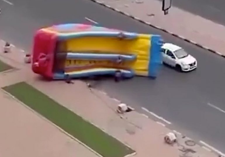 Terrifying moment kids’ bouncy slide rips off its tethers and is blown into busy traffic dragging children with it