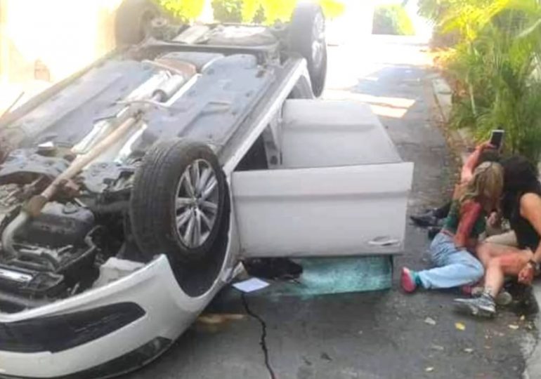 Bizarre moment bloodied crash victims pose for selfies next to wreckage of flipped car after they lost control on road