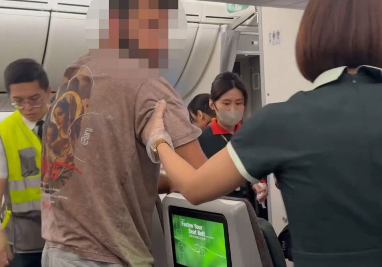 Dramatic moment boozed up passenger is hauled off busy plane after VOMITING on another flier