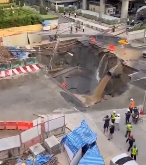 Terrifying moment giant sinkhole threatens to swallow hospital whole as it slowly devours road & cars vanish from sight