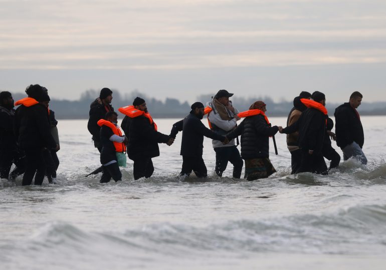 Migrants join hands making way to small boat which eventually collapsed in the Channel en route to UK