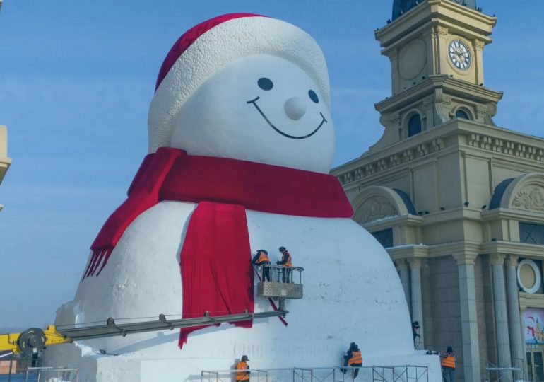 Watch as giant snowman the size of a 6-floor building is constructed in 11 gruelling days… & topped off with a cute grin