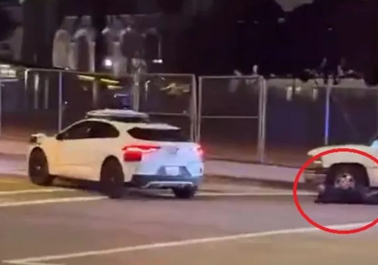 Horror moment self-driving taxi takes passengers into the middle of armed police standoff as cops aim guns at suspect