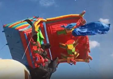 Terrifying moment bouncy castle is flung 30ft in the air during freak windstorm at fair leaving two children injured